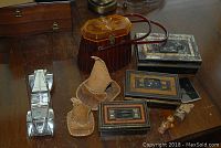 Overview of entire lot including Avon car money box, birch bark moccasin, doll, plastic amber purse, metal boxes, and small carved wooden doll.
