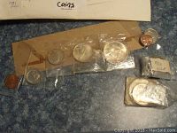 Photo showing multiple Canadian coins from different years, some in plastic bags labeled 1970 and 1971, others loose or in old coin holders.