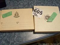 Two beige outer boxes embossed with Canada crest and green repair tape on lids