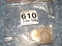 Coins sealed in plastic bags inside a larger plastic bag labeled 610 Silver Dollars.
