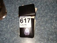 Black leatherette presentation case with Canadian crest and lot sticker, placed on a blue textured countertop.