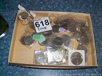 Coins arranged in a cardboard box showing various one dollar coins, some in plastic sleeves and others loose.