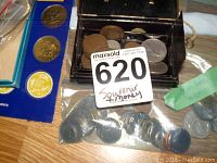 Coins in a small black coin holder box with clear lid, some copper and silver toned coins visible; loose coins in plastic bag