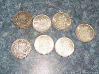 Top view of all 7 Canadian 50 cent coins showing obverse side with Canadian coat of arms and varying wear and patina