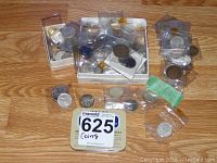 Wide view of multiple coins in plastic sleeves arranged on wooden table with a small tin.