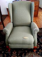 Front view of green La-Z-Boy high back armchair with tear on front seat cushion and carved wood legs.