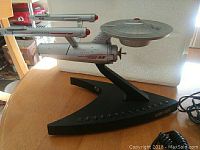 Star Trek USS Enterprise telephone on its stand showing the ship's shape and design from the side.