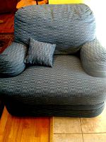 Front view of large blue armchair with matching small pillow on seat, showing patterned fabric upholstery and cover.