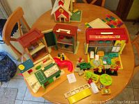 Wide view showing three vintage Fisher Price playsets along with assorted small figures and accessories laid out on a table.