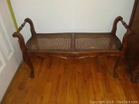 Front and side view of vintage Italian carved wood cane bench showing the curved legs and dual cane seat panels on wooden frame.