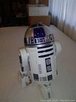 Full view of the Hasbro R2D2 model showing its white body with blue and silver details, standing with one leg extended and an arm slightly raised.