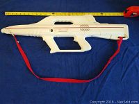 Full side view of the white plastic Lazer Tag gun showing length and red strap.