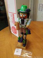 Full view of the Steinbach nutcracker wine grower figurine showing detailed paint and grape clusters with damage visible on the knee.