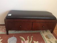 Front view of wooden bench with upholstered faux leather seat showing two drawers closed.