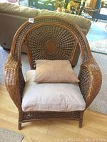 Front angle of rattan chair showing woven design, wooden seat with cushions.