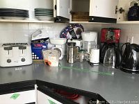 Overview photo of all kitchen appliances on countertop including toaster, coffee makers, kettles, beaters, and kitchen scale.
