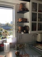 Copper pots and kettle on black corner shelves by window