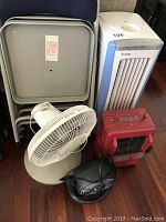 Photo showing three gray folding chairs, white Holmes oscillating fan, red Kenmore heater, black Holmes small space heater, and white and blue Floater air purifier/cooler/humidifier.