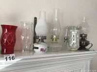 Full view of four oil lamps and mirrored vase on fireplace mantel