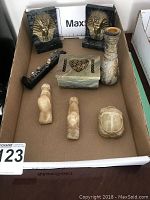 Full view of all decorative items together in cardboard box showing Egyptian scarab, Sphinx bookends, stone box, carved birds, carved vase, and metal railway spike with pewter train