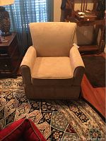 Front angle view of one beige microfiber upholstered rocking chair showing cushion seat and armrest.