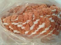 Close up detail of the coral and white geometric pattern of the rug inside sealed plastic packaging.