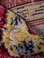 Close-up showing thick plush yarn pile texture and multicolored fibers including yellow, red, and white.