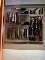 Organized closet showing Closetmaid adjustable wire shelves and hanging rods with clothes, pillows, and shoes.