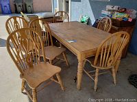 Photo showing rectangular wooden dining table surrounded by six matching spindle-back chairs.