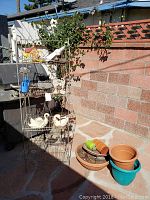 Full view of wire rack with various decorative swan planters and garden pots placed on and around it against brick wall.