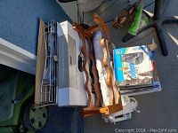 Two metal roll out cabinet drawers stacked on top of each other, beside a wooden wine rack and boxes with kitchen items.