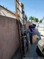 Two extension ladders leaning against a block wall outdoors, showing weathered surfaces and metal rungs.