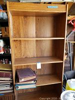 Wooden 4-shelf book case with three photo albums on the middle shelves, showing medium oak finish.