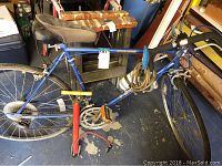 Full side view of the blue 12 speed bicycle with pump underneath.