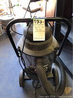 Front view of Shop Vac with attached hose and handle showing label and condition.
