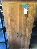 Front view of a wooden cabinet with two doors closed, showing metal handles and natural wood grain finish.