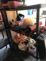 Black plastic shelving unit with various tools and items on the shelves, showing overall structure and condition.