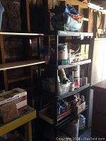 Full view of black plastic shelving unit filled with various paint supplies and boxes.