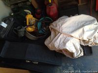 Full lot showing beige car cover, black ramps, and other supplies in the background