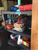Two shelves filled with assorted tools including soldering guns, inflator, and nail gun mostly in original packaging.