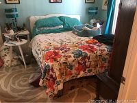 Photo of queen size bed with floral bedding and teal pillows showing the assembled Sleep Number adjustable mattress on a base under a window.