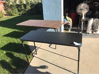 Two folding tables side by side outdoors, showing the difference in size and surface materials.