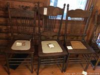 Photo of three vintage wooden chairs: two with needlepoint floral cushions and one with cane seat, showing wear.