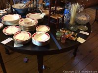 Dark wood round table with five legs holding dishes and small decorative items on the surface.