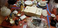 Table top showing assorted costume jewelry, small perfume bottles, Limoges box, candles and other small decorative collectibles.