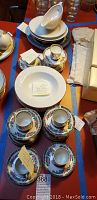 Photo showing several demitasse cups with saucers, stacked bowls, and some wrapped Willow pattern pieces, depicting the variety in the lot