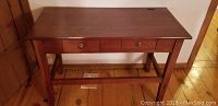 Front view of wood side table showing two drawers with brass knobs and lower stretcher shelf