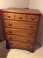 Front view of wooden chest of drawers showing 5 drawers with antique-style metal handles and smooth wood finish.