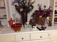 Full view of lot showing glass basket, faux flowers in metal vase and planter, orange lidded dish, and figurines