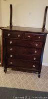 Full front view of the dresser showing six drawers, dark wood finish, curved sides, and two uprights for a missing mirror.